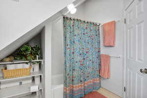 Full bathroom featuring shower / bath combo and lofted ceiling