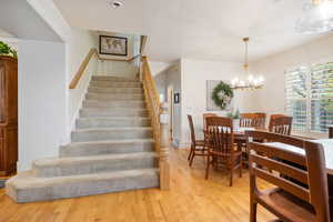 Stairway with wood finished floors, a chandelier, and a textured ceiling