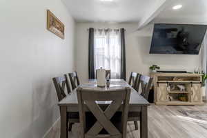 Dining area featuring light wood-style flooring and beam ceiling