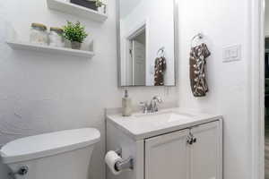 Half bathroom featuring a textured wall and vanity