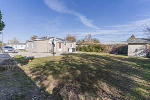 View of green lawn with a patio and an outbuilding