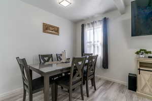 Dining area featuring light wood-style flooring and beam ceiling