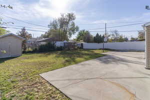 Fenced backyard featuring a patio and a shed