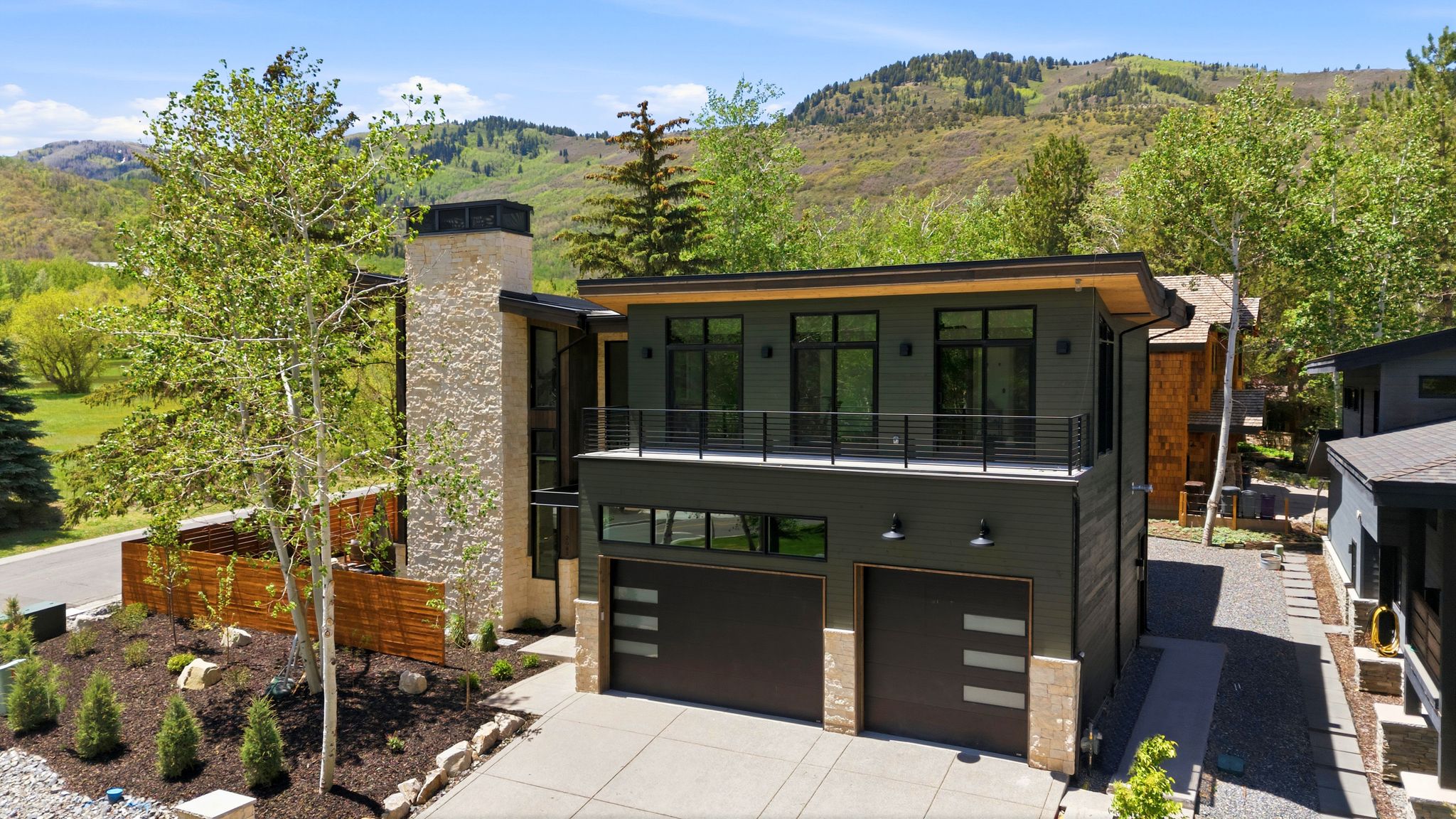 Contemporary exterior featuring dark paneling, a prominent stone-clad chimney, and a flat roofline