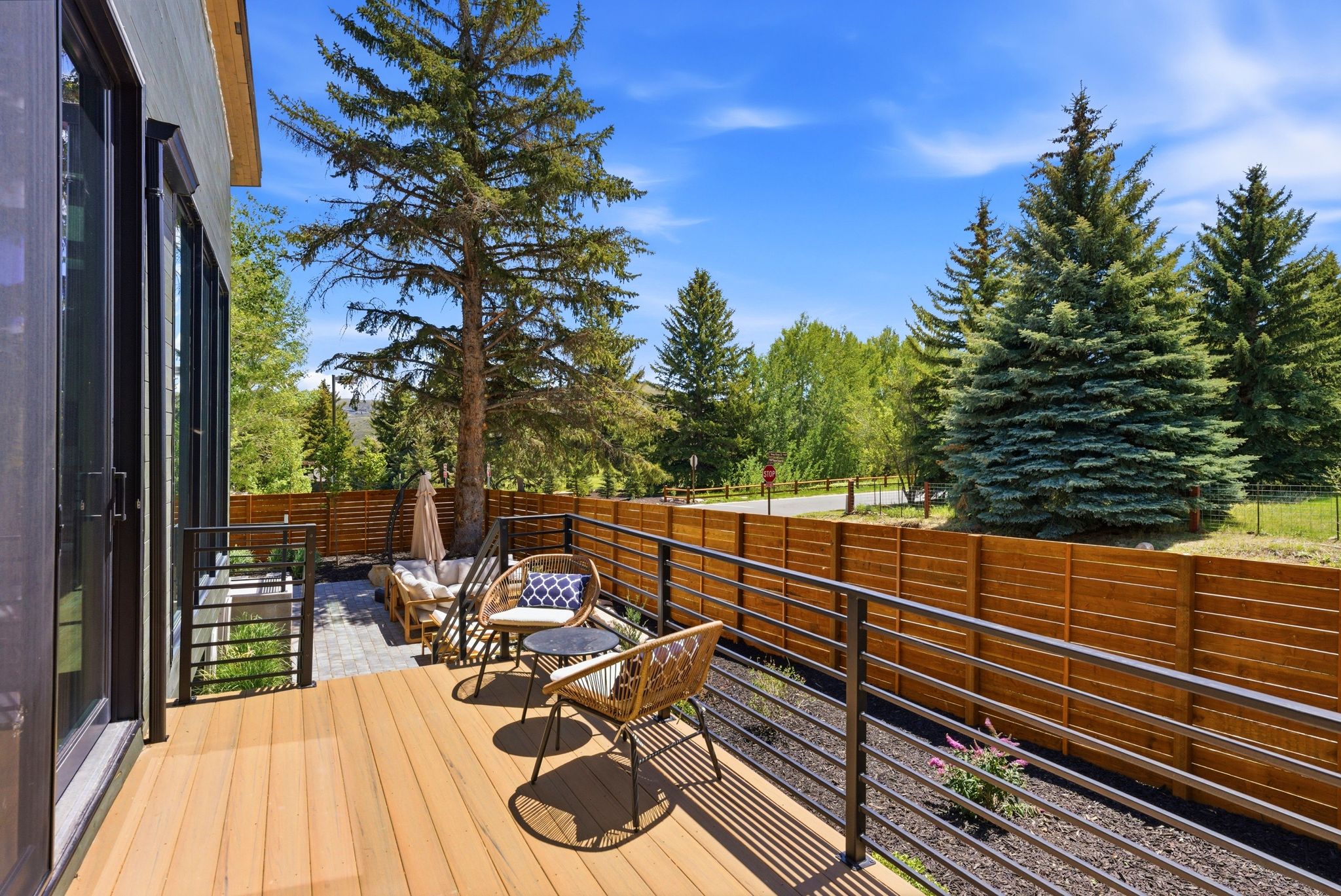 Expansive outdoor deck with natural wood-tone flooring and contemporary metal railing