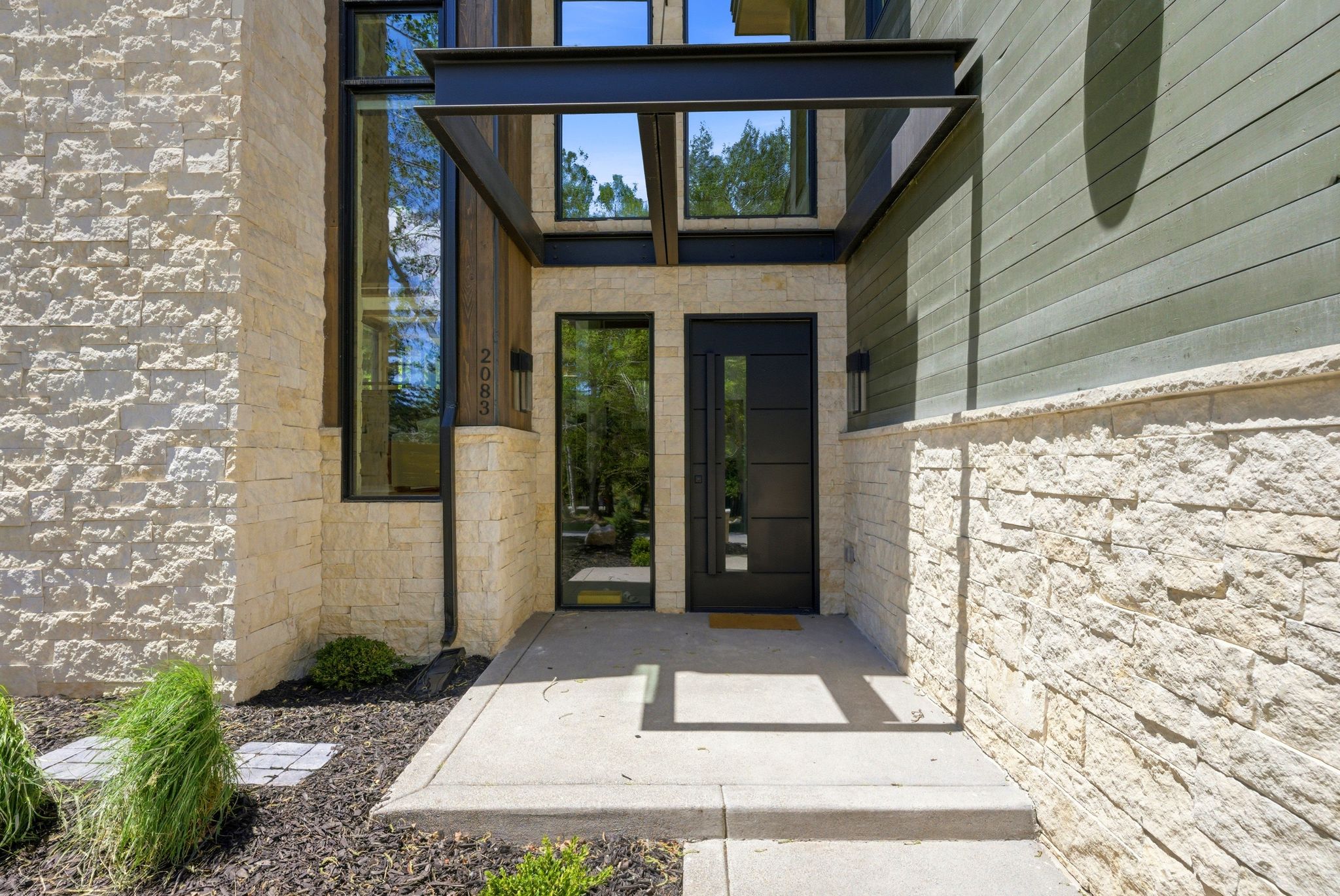 Modern entry featuring a black paneled door with a single vertical window, flanked by a full-height sidelight