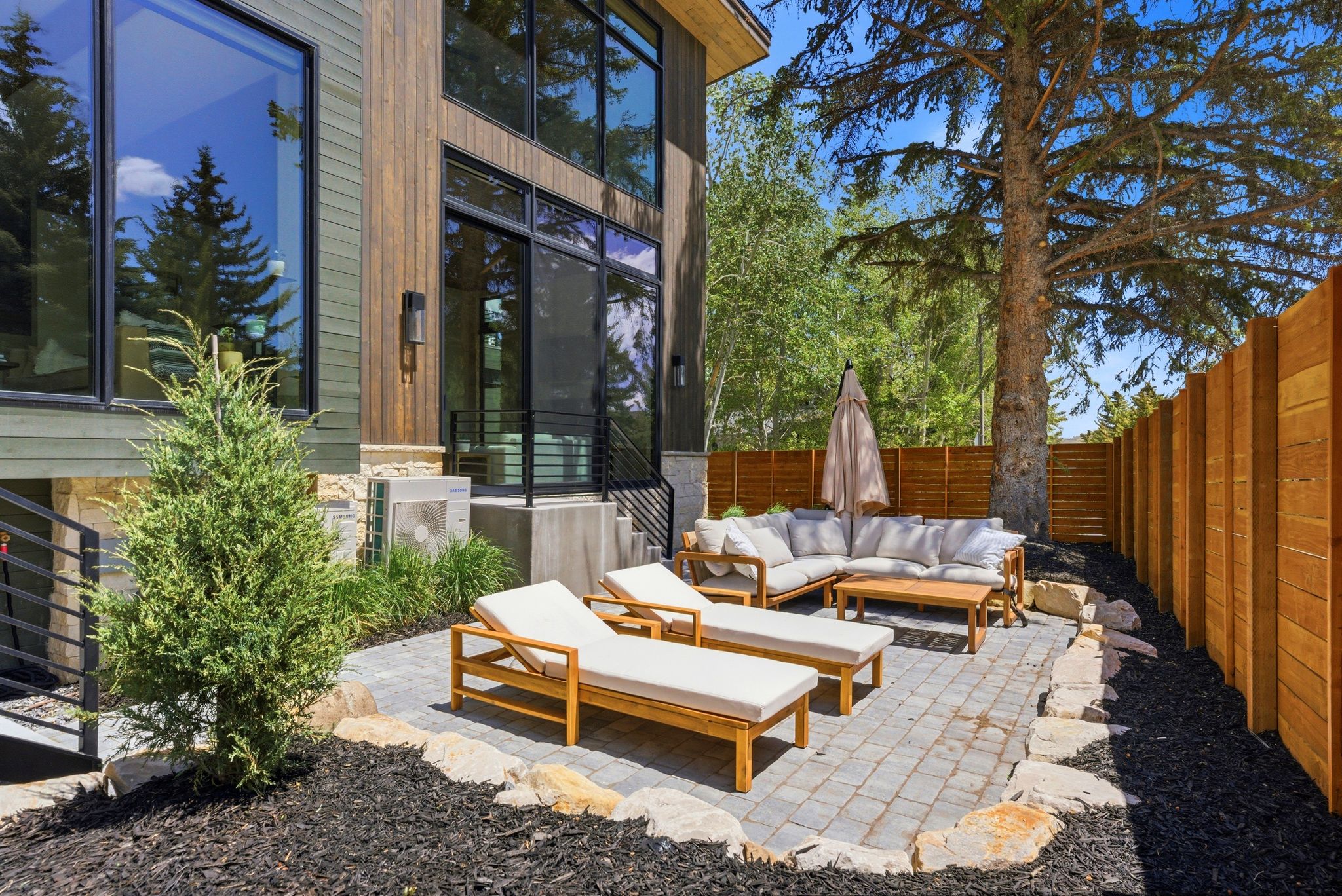 Paved patio area featuring a slatted wood privacy fence and natural stone accents