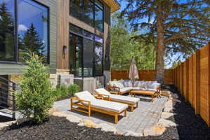 Paved patio area featuring a slatted wood privacy fence and natural stone accents