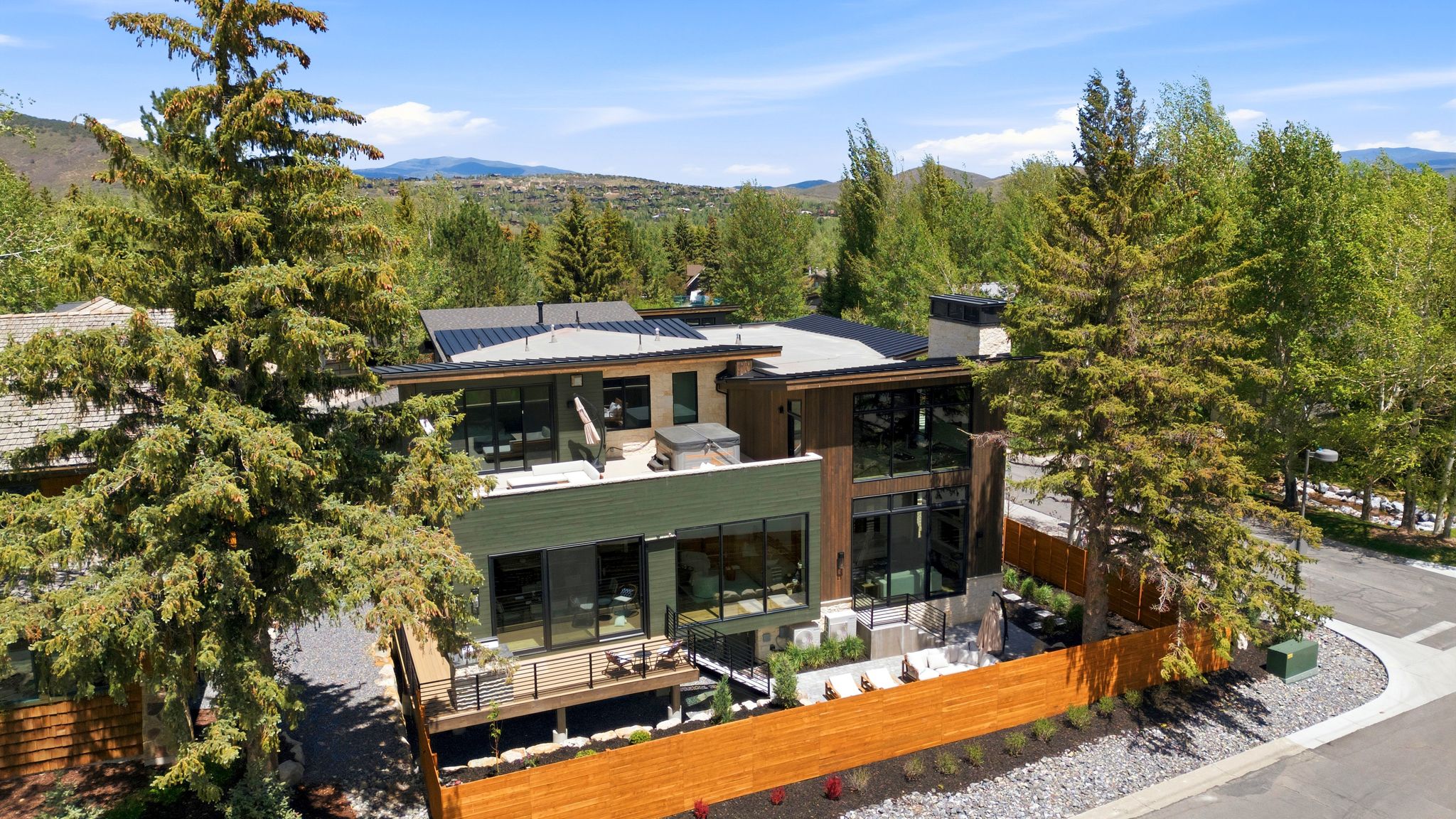 Contemporary multi-level residence featuring expansive windows, a flat roofline, and a private deck with a hot tub
