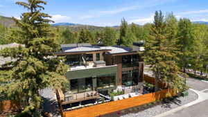 Contemporary multi-level residence featuring expansive windows, a flat roofline, and a private deck with a hot tub
