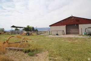 View of yard featuring a detached garage, an outbuilding, and a rural view
