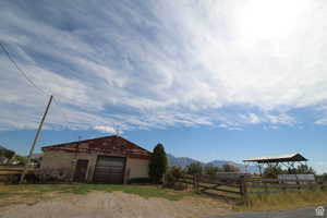 View of front facade featuring an outdoor structure, a mountain view, a detached garage, driveway, and a view of countryside