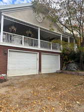 View of front of property with a garage, brick siding, driveway, and a balcony