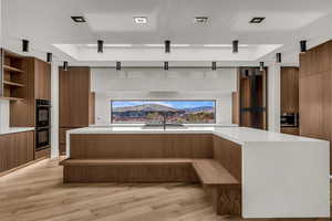 Kitchen featuring brown cabinets, modern cabinets, open shelves, light stone countertops, and light wood-style flooring