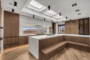 Kitchen with a skylight, modern cabinets, brown cabinets, and light stone counters