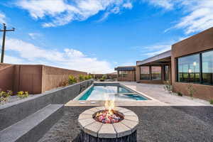View of pool featuring a fenced backyard, a patio, an outdoor fire pit, and a pool with connected hot tub