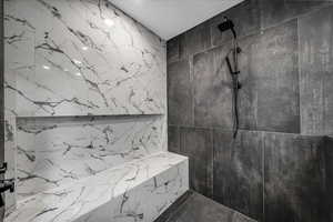 Full bath with a marble finish shower