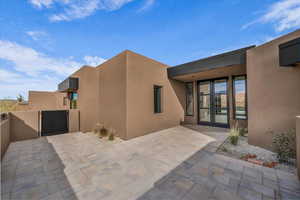 Entrance to property with stucco siding, a patio, and a gate