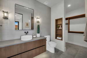 Full bathroom with vanity, built in shelves, concrete floors, and recessed lighting