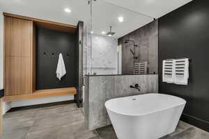 Bathroom with a marble finish shower, recessed lighting, a freestanding bath, tile walls, and a towel warming rack