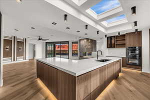 Kitchen featuring modern cabinets, open floor plan, open shelves, light wood-style flooring, and a spacious island