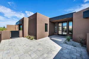 Doorway to property with a gate, stucco siding, and a patio area