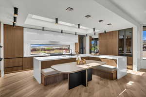 Dual tone kitchen with modern cabinets, a skylight, light stone counters, light wood-style flooring, and dual tone cabinets