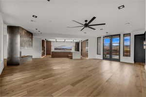 Unfurnished living room featuring light wood-style floors, a barn door, a fireplace, and ceiling fan