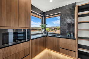 Bar featuring stainless steel microwave, modern cabinets, a mountain view, wood finish cabinetry, and recessed lighting