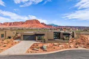 View of front facade with stucco siding, decorative driveway, a mountain view, and an attached garage