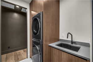 Laundry room with stacked washing machine and dryer and wood finished floors