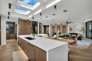 Kitchen featuring modern cabinets, light wood finished floors, light stone countertops, and a large island with sink