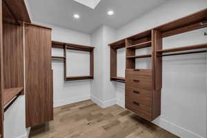 Walk in closet with light wood-type flooring and a skylight