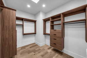 Walk in closet with light wood-type flooring