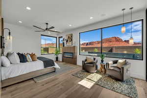Bedroom featuring wood finished floors, recessed lighting, a ceiling fan, and a glass covered fireplace