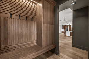 Mudroom with light wood-type flooring, wooden walls, ceiling fan, and a barn door