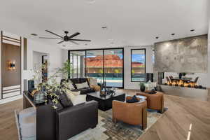 Living area featuring ceiling fan, light wood finished floors, and expansive windows