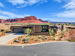Pueblo revival-style home featuring stucco siding, a mountain view, driveway, and an attached garage