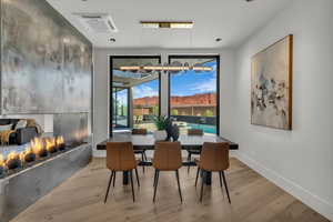 Dining space with wood finished floors and a warm lit fireplace