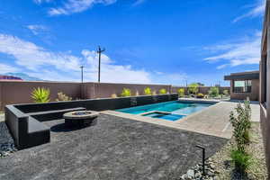 Integrated pool / hot tub featuring a patio area, a fire pit, and a fenced backyard