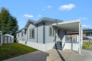 View of front of property featuring a storage unit, a front yard, and covered porch