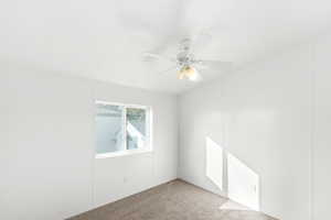 Carpeted spare room with a ceiling fan