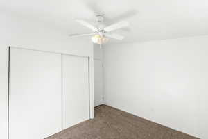 Unfurnished bedroom with carpet, ceiling fan, and a closet