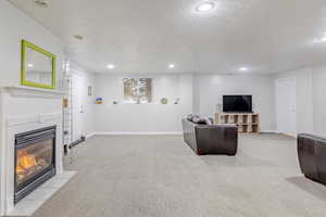 Living area with light carpet, a fireplace with flush hearth, recessed lighting, and a textured ceiling