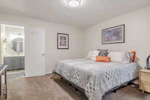 Bedroom with carpet flooring, a textured ceiling, and connected bathroom