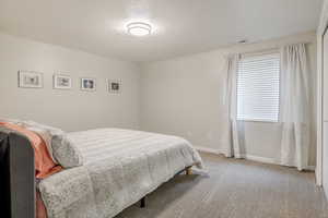 Bedroom with light colored carpet and a textured ceiling