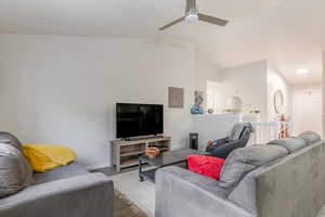 Living room featuring lofted ceiling, wood finished floors, and a ceiling fan
