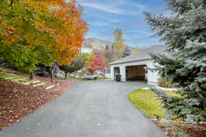 View of side of home with a mountain view, a garage, driveway, and stucco siding