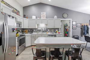 Kitchen featuring stainless steel appliances, a kitchen breakfast bar, light wood-type flooring, a center island, and white cabinets