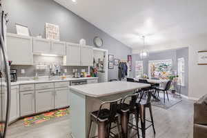 Kitchen featuring a breakfast bar area, light countertops, lofted ceiling, light wood finished floors, and a center island